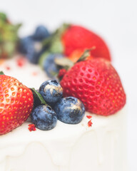 strawberries and blueberries on a cake. vertical photo of a cake with berries.
