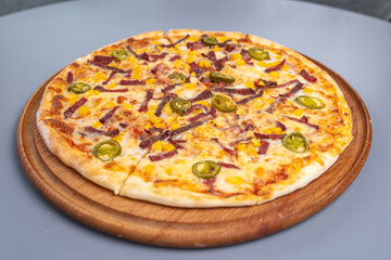 pizza with peppers and sausages on a wooded board
