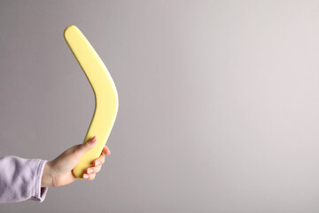 Woman holding boomerang on grey background, closeup. Space for text