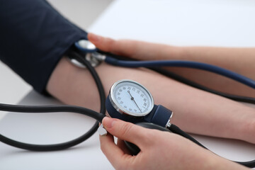 Doctor checking blood pressure of woman in clinic, closeup