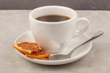 Cup of coffee on a neutral background with citrus chips