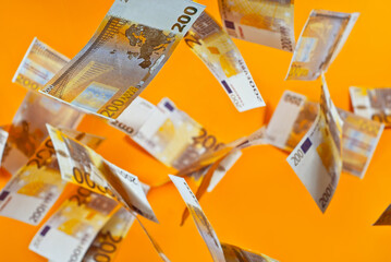Yellow dollar bills on an orange background. 200 euro banknotes close up. Money flies in the air.