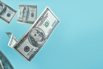 Green dollar bills on a blue background. 100 dollar bills close up. The concept of wealth and success. Money flies in the air. Copy space and free space for text near money.