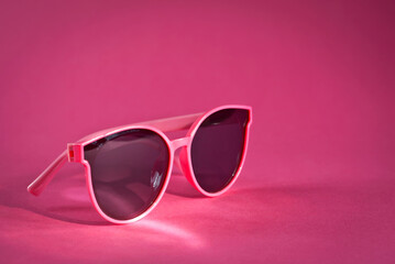 Sunglasses on a pink background. Women's glasses close up. Copy space and place for text near the glasses.
