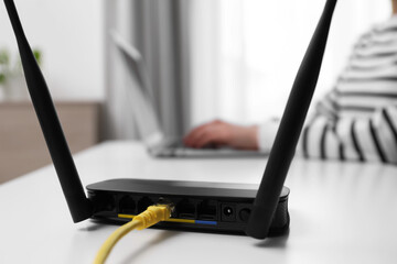 Woman working in office, focus on connected with cable router. Wireless internet communication