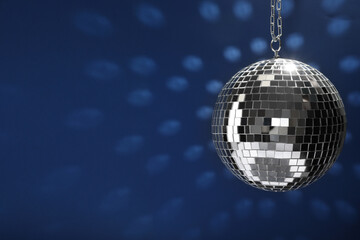 Shiny disco ball on blue background, space for text