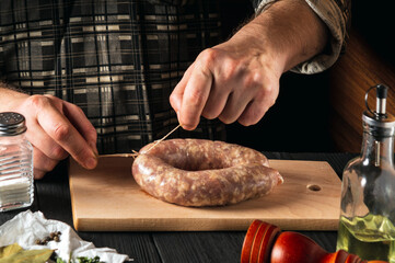 Close-up hands of a cook or chef tying a thread of homemade sausage. Cooking sausages with meat and spices on a cutting board