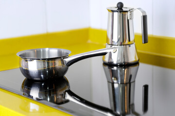 Little stainless steel pot and geyser coffee maker in kitchen on the induction panel