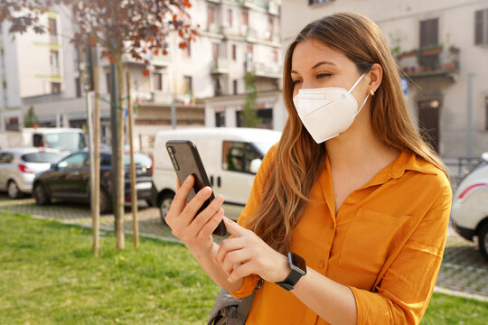 Pretty Girl With Smartwatch Wearing KN95 FFP2 Face Mask Using Mobile Phone In City Street