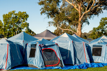 Tents setup for a group camping at the green grass meadow. Multiple instant up connectable tents on a campground.