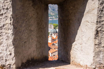View of the Church of St. Nicholas through the loophole of the protective wall of the fortress in the town of Kotor. Montenegro 