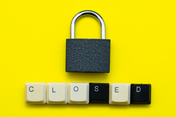 closed padlock with keys on a yellow background at the bottom the inscription closed laid out from the keys of a computer keyboard concept prohibitions data protection