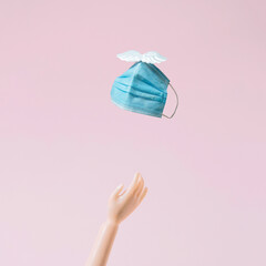 End of epidemic and corona. Removing the mask. Freedom. A flying mask. Pink wallpaper. Minimal composition.