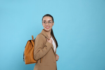 Beautiful young woman with stylish leather backpack on turquoise background. Space for text