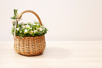 Fototapeta na wymiar A wicker basket with a bouquet of white bush roses and ornamental grass is on the table. Copy space
