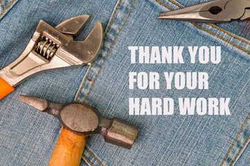 Phrase THANK YOU FOR YOUR HARD WORK written on blue jeans with hammer, wrench and pliers.