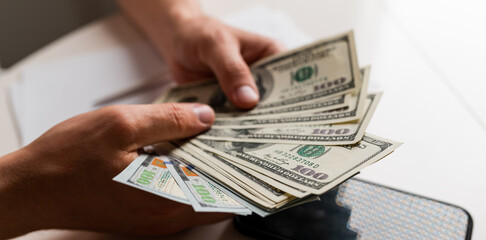 Male hands counting US Dollar bills or paying in cash on money background. Concept of investment, success, financial prospects