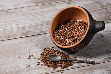 brown rice in ceramic bowl with metal spoon on wooden background