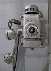 Old metal wall-mounted telephone with rotary dial. Antique phone with dial