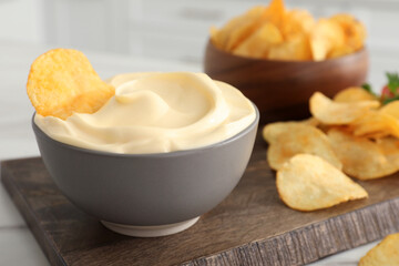 Potato chips and mayonnaise on wooden board, closeup
