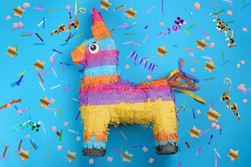 Bright funny pinata and party decor on blue background, flat lay