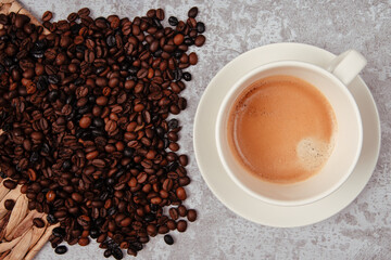 Rustic cement countertop with a cup of coffee and a handful of coffee beans.