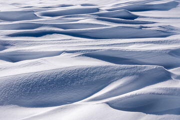 Perfect abstract texture of winter snow, mounds of frozen blue snow. Wavy surface of firn field