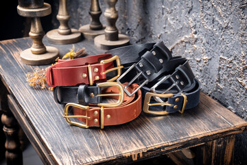 Six leather multi-coloured straps lie on a wooden table against a backdrop of vintage candles.