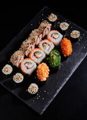 Japanese sushi food. Maki ands rolls with tuna, salmon, shrimp, crab and avocado on stone slate.