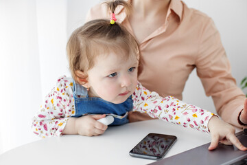 The little daughter prevents her mother from working at the computer. Work from home online. Work in the decree.