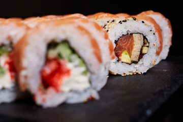 Selective focus. Close up of sliced piece of sushi roll with salmon, tuna and avocado.