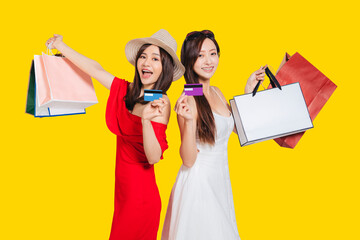  happy young women dressed in summer clothes holding shopping bags and credit cards