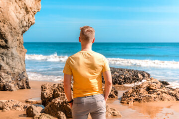 Blonde man stands with his back to Matador Beach, California