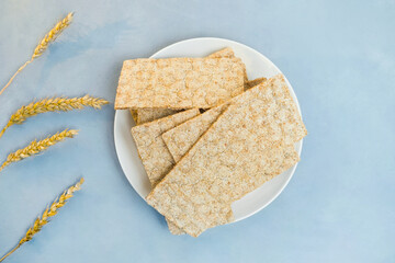 Wholegrain wheat bread crisps on plate and wheat ears. Table top view. Healthy nutrition concept. Healthy breakfast, dietetic products.