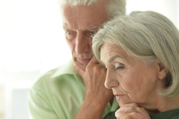Portrait of sad senior couple posing at home