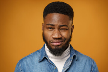 Obraz premium Young african american man frowns face being displeased against yellow background