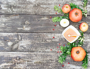 Large banner with traditional symbols for jewish holiday- apples, pomegranate, cup with honey, and green branch on wooden background. Concept Rosh Hashanah tova jewish New Year. Top view, fresh fruits