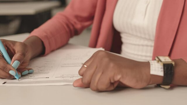 Steadicam of hands of cropped unrecognizable student with manicure, taking exam, using cheat sheet with answer to test, hiding tiny piece of paper under watch belt