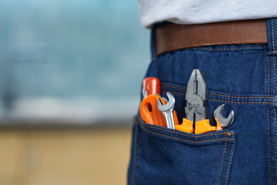 Close up shot of various plumbing hand tools in man's jeans back pocket