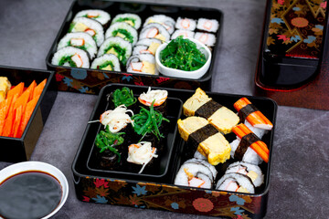 Set of variety sushi, Tamagoyaki, crabsticks sushi and maki in bento box served with soy sauce and wasabi. Delicious japanese food.