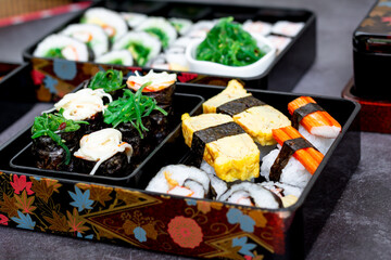 Set of variety sushi, Tamagoyaki, crabsticks sushi and maki in bento box served with soy sauce and wasabi. Delicious japanese food.