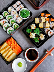 Set of variety sushi, Tamagoyaki, crabsticks sushi and maki in bento box served with soy sauce and wasabi. Delicious japanese food. Top view.