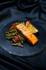 grilled salmon with vegetables on a black background