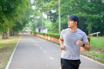Asian handsome young man Doing exercise by running in the park Sweating from morning workouts
