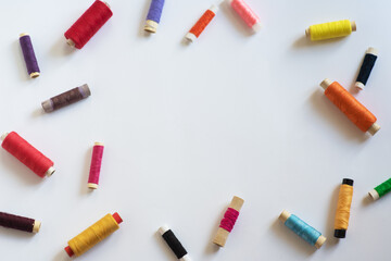 Frame with multi-colored reels with threads on a white background. Top View