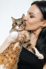 Young beautiful brunette kissing a cat in her arms