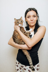 Beautiful brunette girl holding a cat in her arms with a surprised face