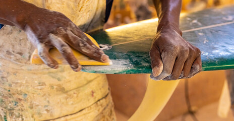 An African Craftsman surfboard Shaper working in a repair workshop