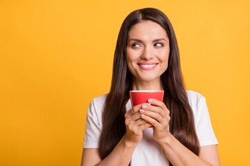 Photo of dreamy positive relaxed woman hold mug look stand empty space isolated on vivid yellow color background