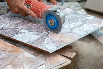 Close-up floor tiles are being cut with an electric cutter by builders.